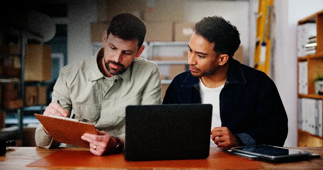 Two Nymbus team members collaborating over a laptop and clipboard.