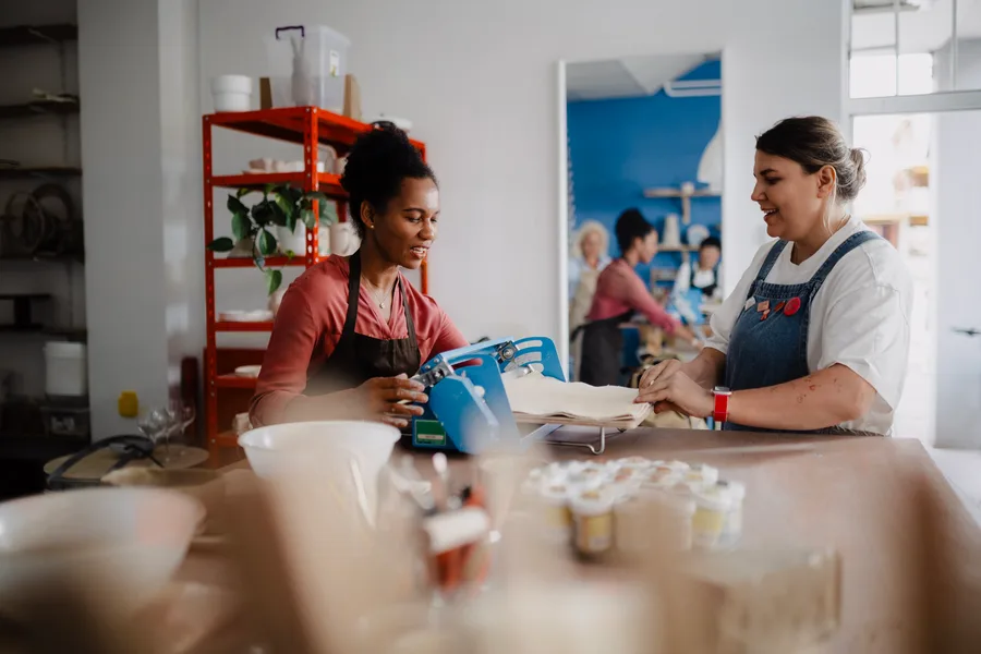 Two small-business owners working together at a pottery studio counter.